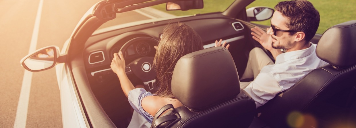 Man en een vrouw in een cabrio aan het rijden op een weg